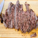 marinated flank steak cut up on a cutting board
