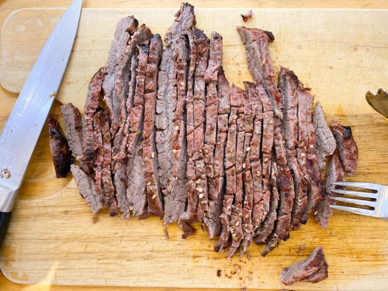 marinated flank steak cut up on a cutting board