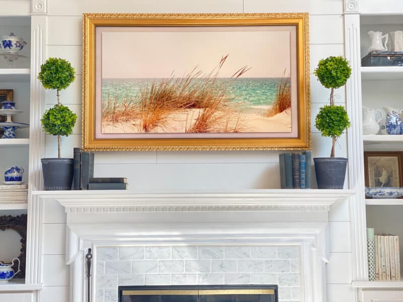 photo of the faux topiaries flanking our frame tv on the fireplace mantel