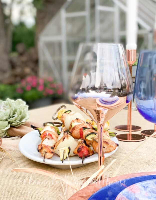 outdoor tablescape with chicken kabobs on table that is decorated with decoupaged napkin plates