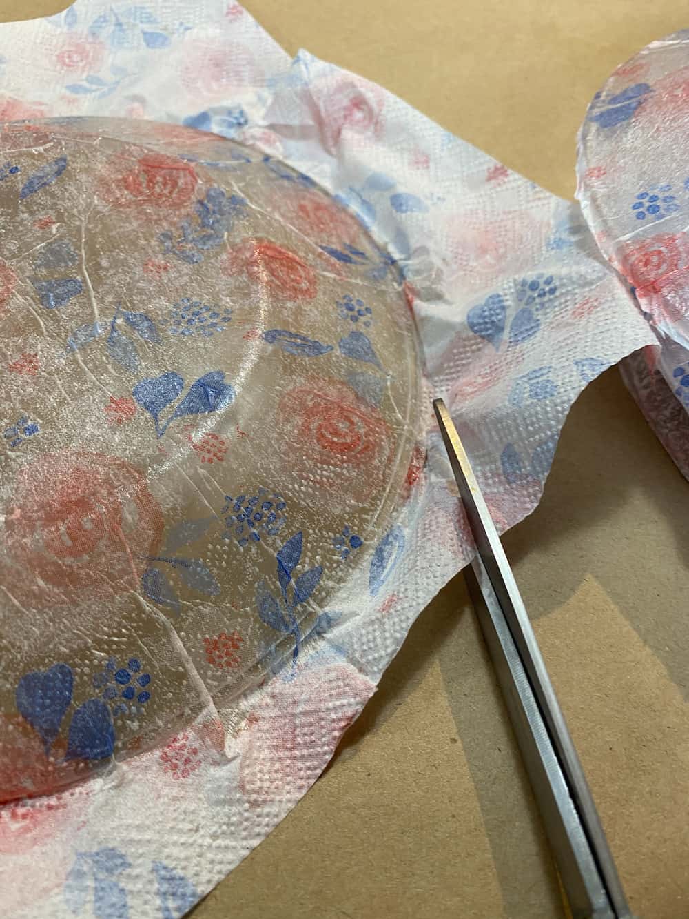 Trimming the paper napkin that has been decoupaged to a glass plate