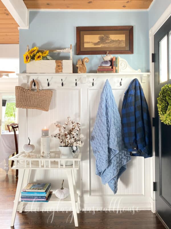 the entry way hook wall with a blue throw and plaid jacket hanging from it.