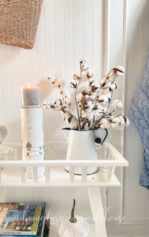 simple fall decor in my front entryway. a candle with an antique coffee pot filled with cotton stems