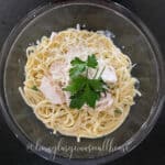 Easy homemade Alfredo Sauce over pasta in a bowl with chicken for serving