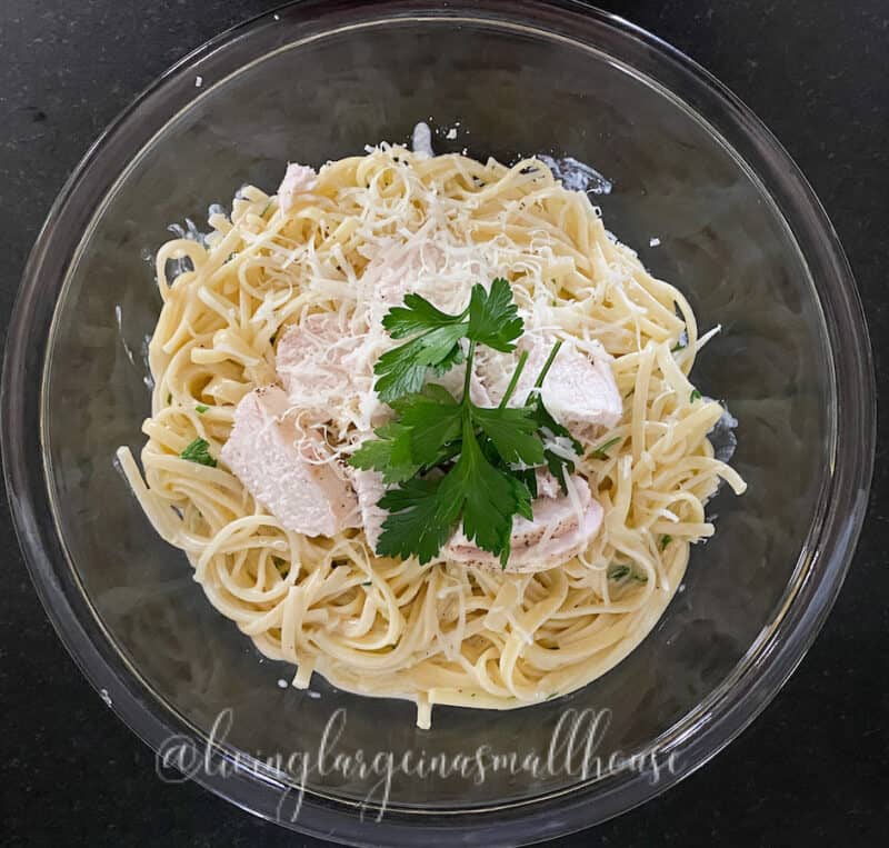 Easy homemade Alfredo Sauce over pasta in a bowl with chicken for serving