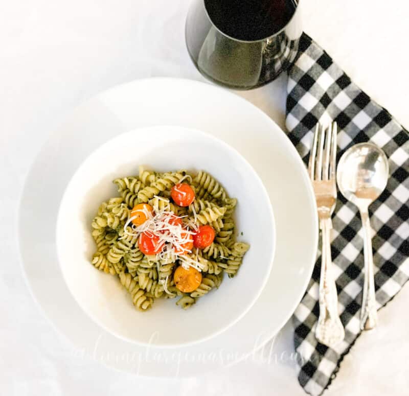 table set with bowl of roasted cherry tomato & pesto pasta