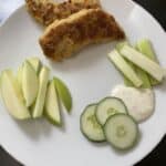 gluten-free chicken strips plated with ranch dressing dip, apple slices and raw vegetables.