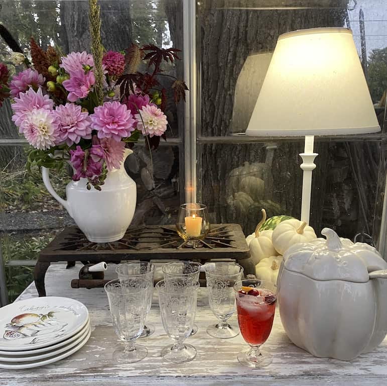 picture of a table set with a floral arrangement, candles and a tureen with Friendsgiving punch