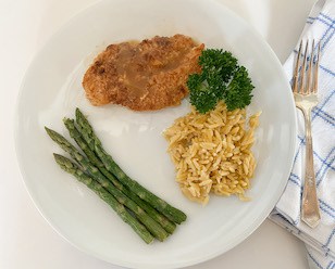 plated lemon chicken with Orzo and Asparagus garnished with parsley