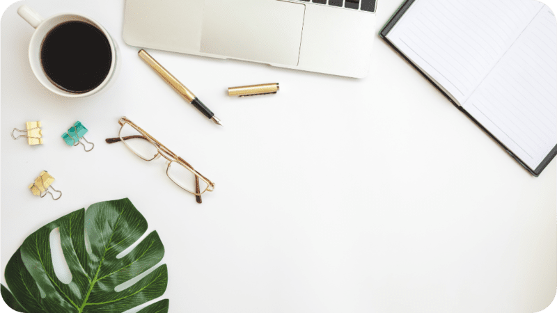 photo graphics of the desk of a blogger with a computer, glasses and a pen. for the post "how does a blogger make money?