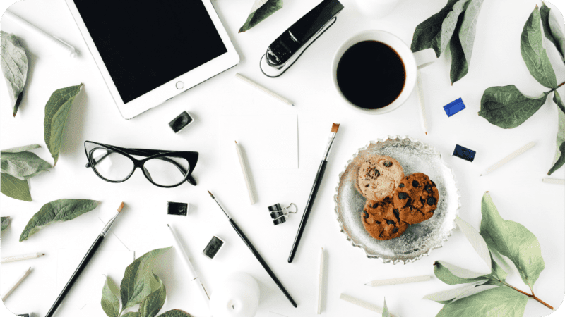 photo graphics of the desk of a blogger with a computer, glasses and a pen. for the post "how does a blogger make money?