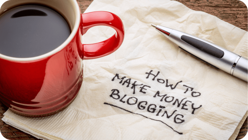 a photo of a coffee cup and a napkin that has writing that says "How to Make Money Blogging"