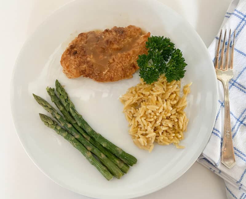 plated lemon chicken with Orzo and Asparagus garnished with parsley