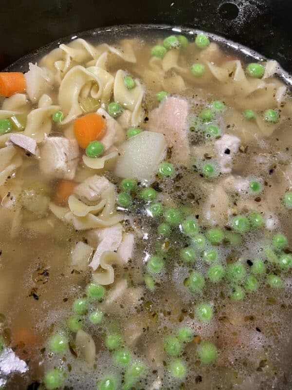 classic chicken noodle soup simmering in the stock pot