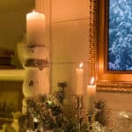 the corner of the mantel with candles lit and greenery