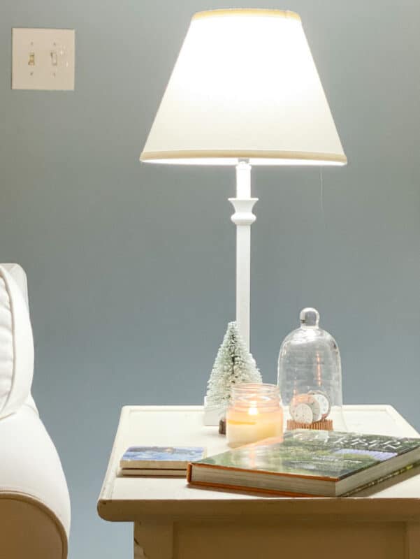 Small table and lamp with a book and a candle next to chair for cozy reading