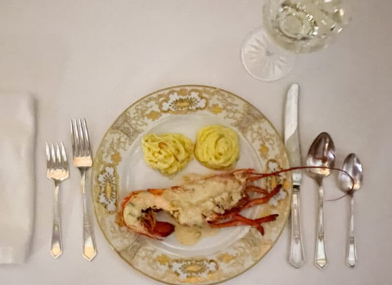 china plate with lobster and potatoes on a white table cloth