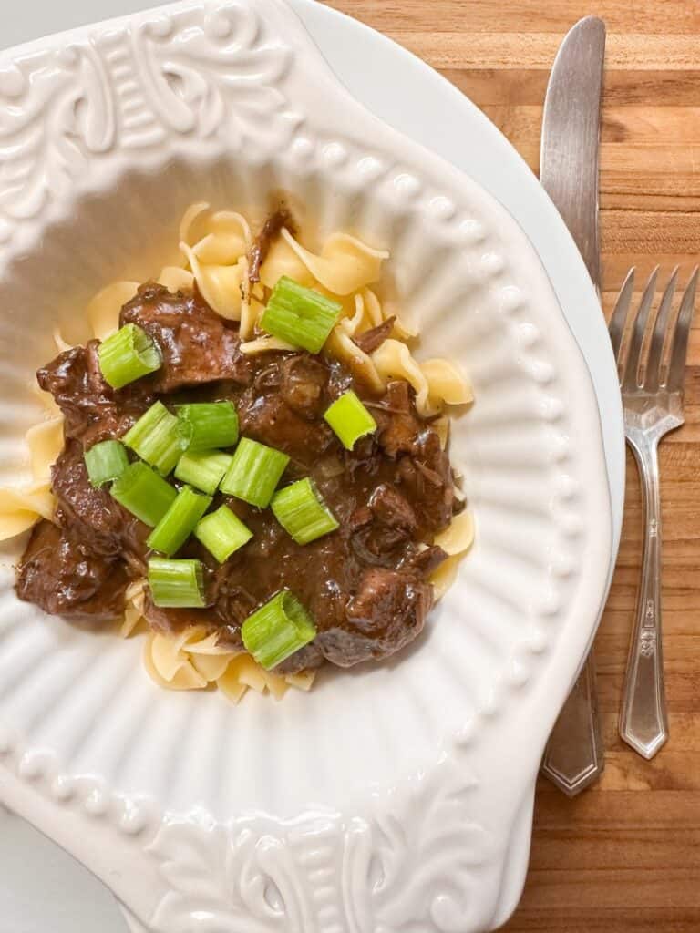 Beef sirloin tips and onion gravy in a bowl garnished with green onions