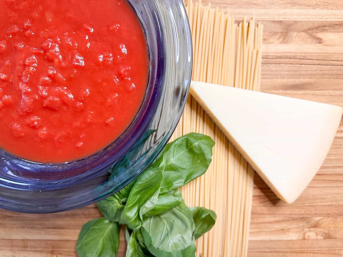 ingredients for bucatini pomodoro. Tomatoes, Basil, pasta and parmesan cheese.