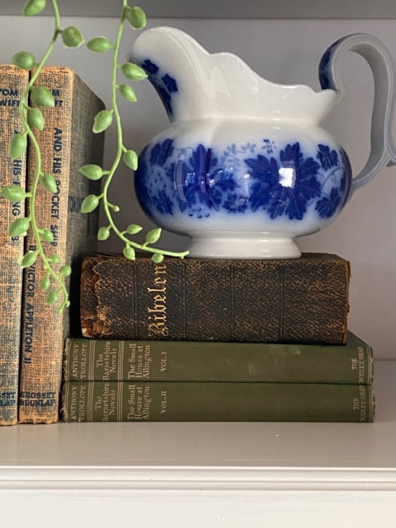 a flow blue pitcher on top of old vintage books