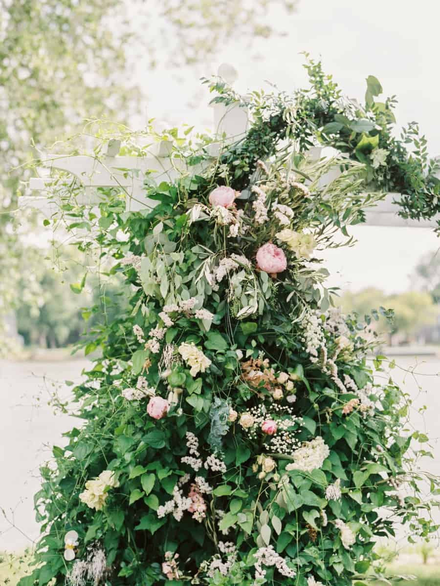 the greenery and florals over the arbor which was where the couple were married in this intimate vintage backyard wedding