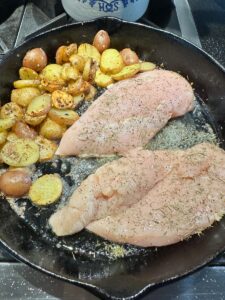 cooked potatoes in cast iron pan with chicken breast added
