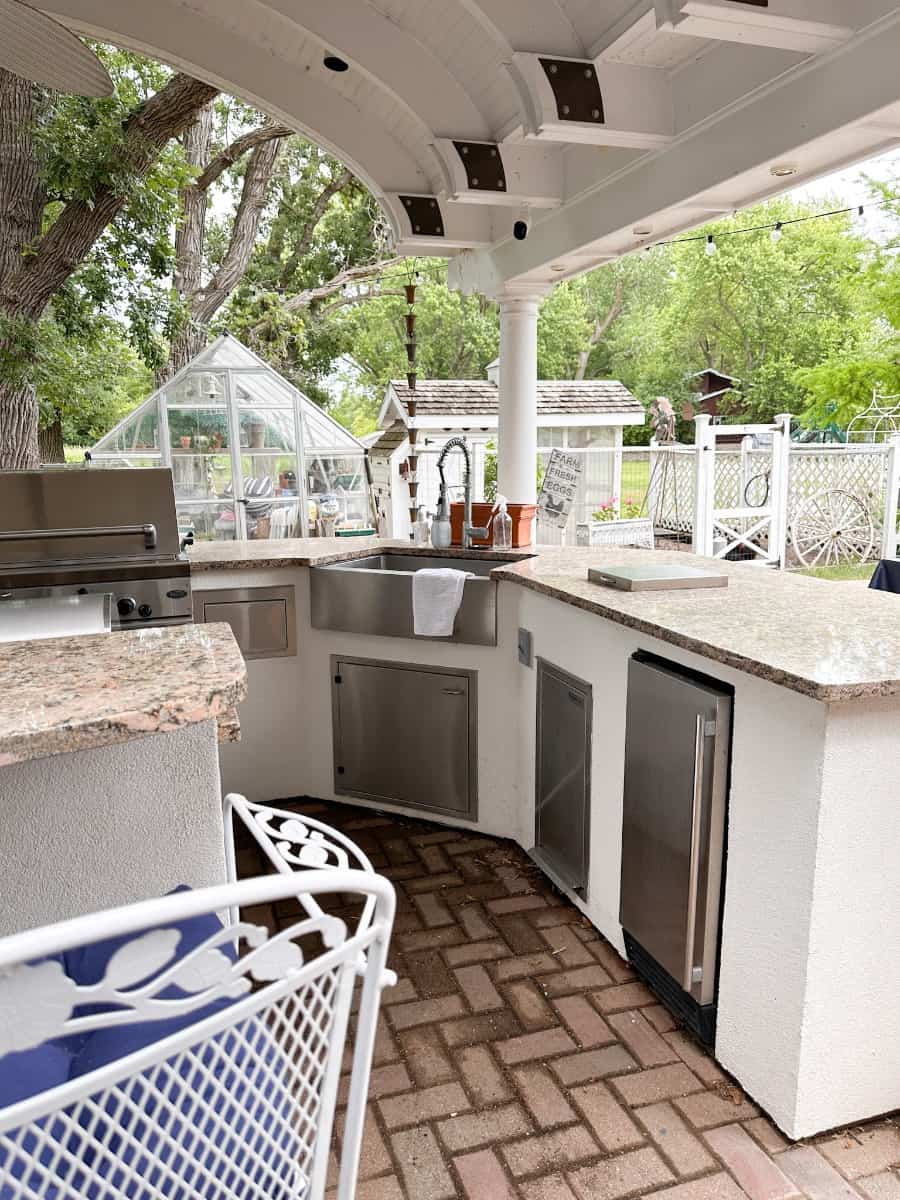 outdoor kitchen with a view of the sink, garbage can, ice maker and the grill