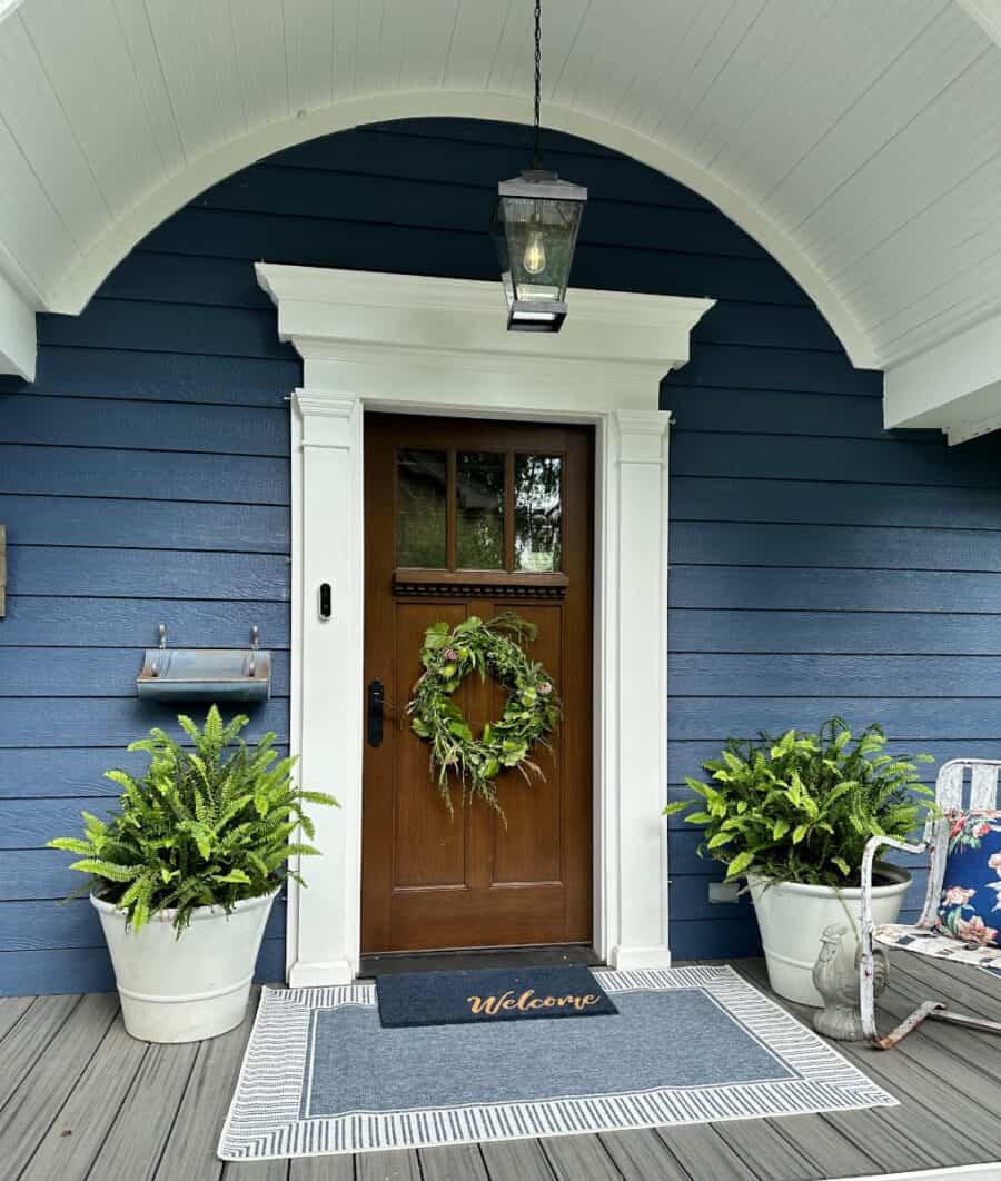 front door with live wreath and fern potted in a large white pot