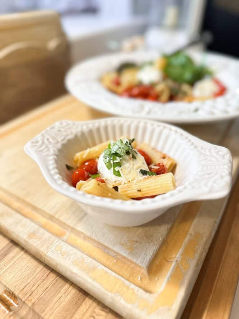 pasta with burst cherry tomatoes and burrata cheese in a bowl