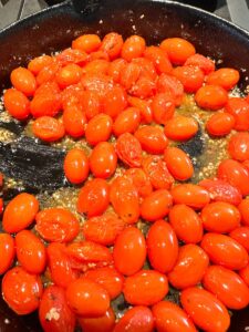 cherry tomatoes that have bursted after roasting in a cast iron pan for about 20 minutes