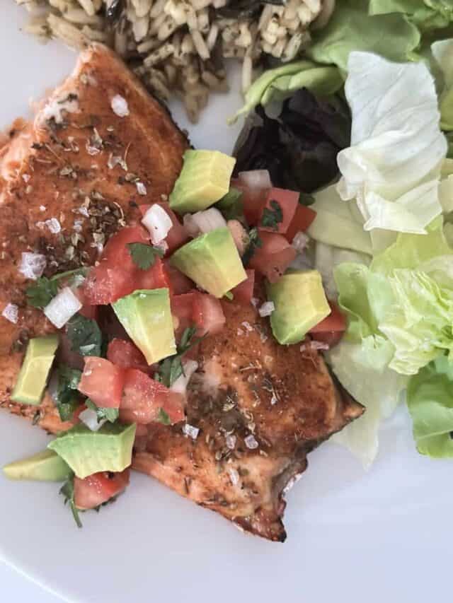 piece of cooked cajun salmon with avocado pico de Gallo on a plate