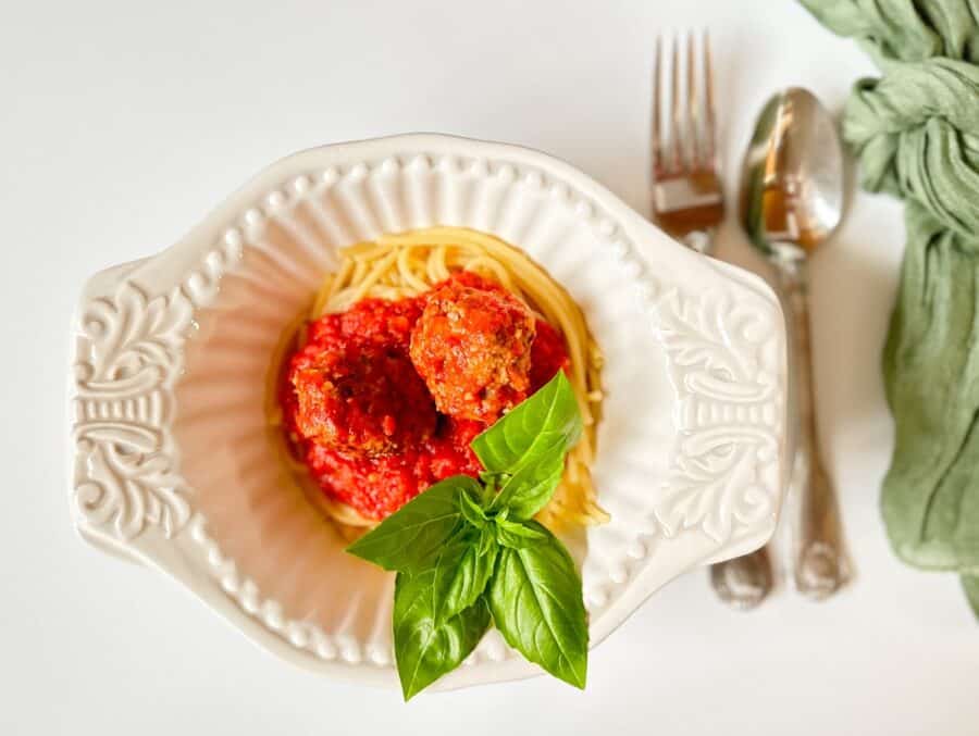 pasta, marinara and italian meatballs in a white bowl ready to eat.