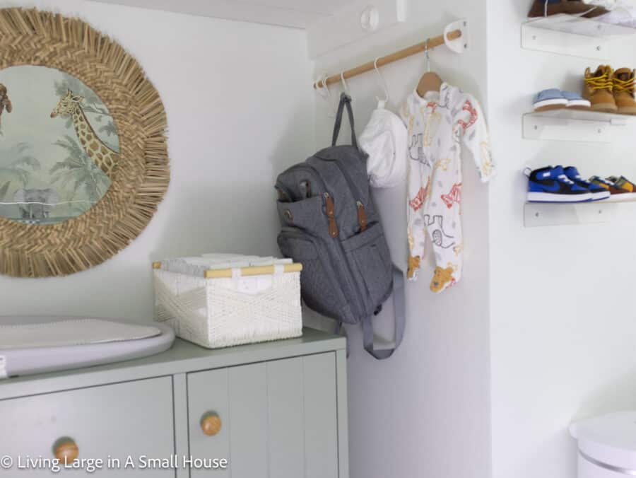 a view of the nursery closet with a dresser in it along with a changing area and hanging rod.