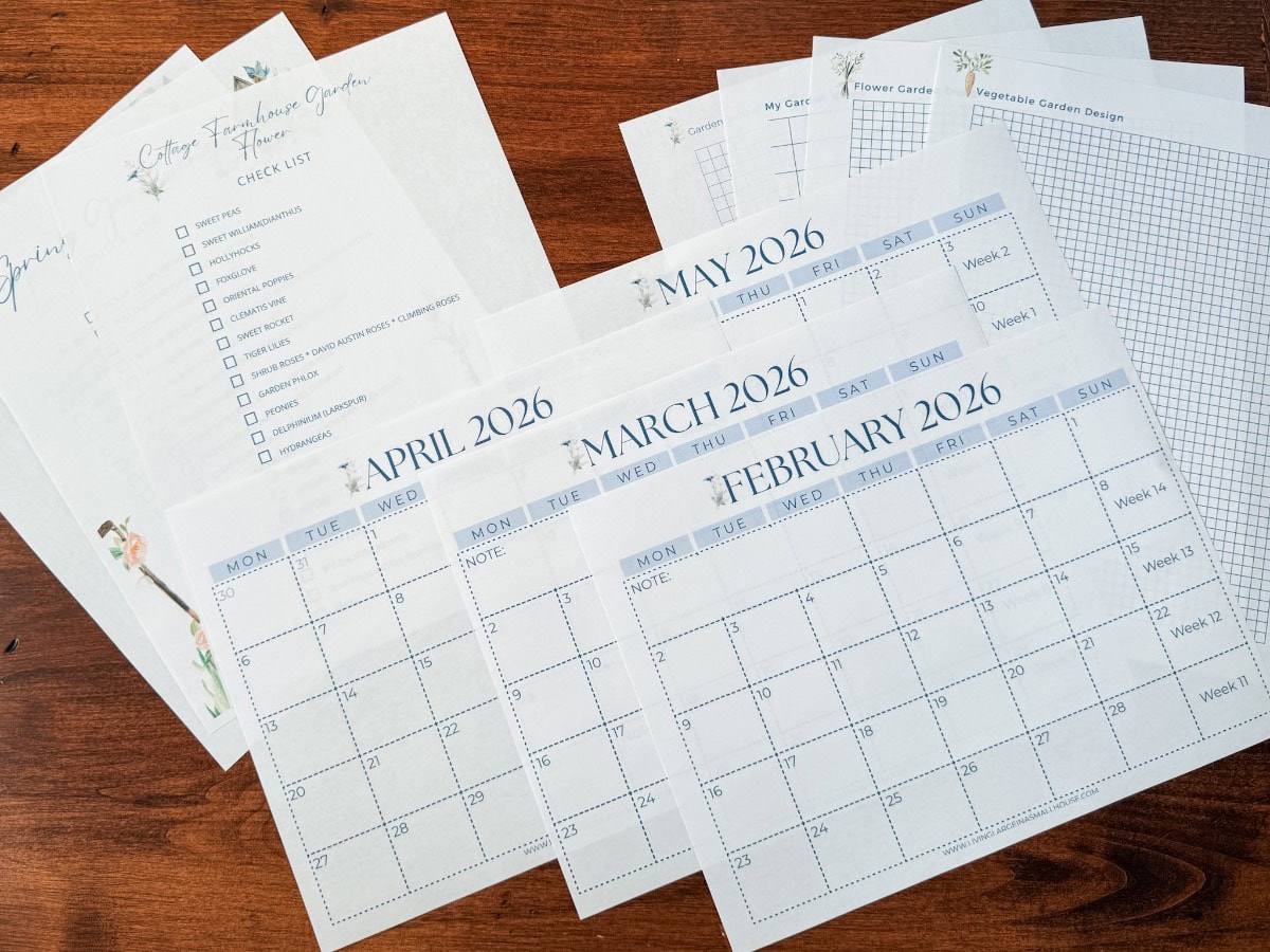 A set of gardening planning sheets and printed monthly calendars for February to May 2026, plus grid charts and checklists for starting seeds indoors in Zone 5b, are spread out on a wooden surface.
