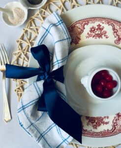 place setting with a white and blue napkin tied with a blue ribbon