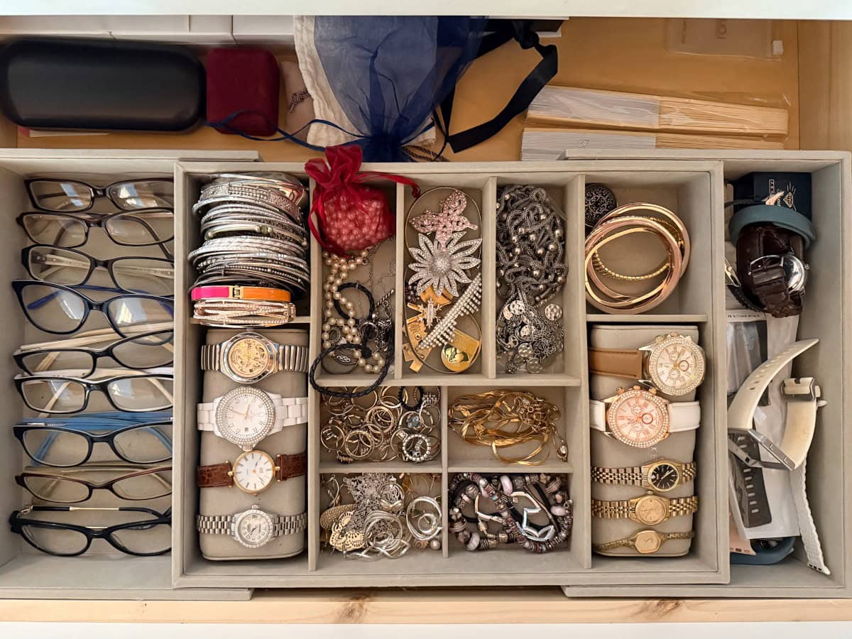 A drawer organizer holds multiple pairs of eyeglasses, wristwatches, bracelets, rings, and more in separate compartments—perfect for those seeking organizing tips for bedrooms and bathrooms.