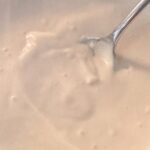 A close-up of a spoon in a bowl of thick, creamy spicy sauce
