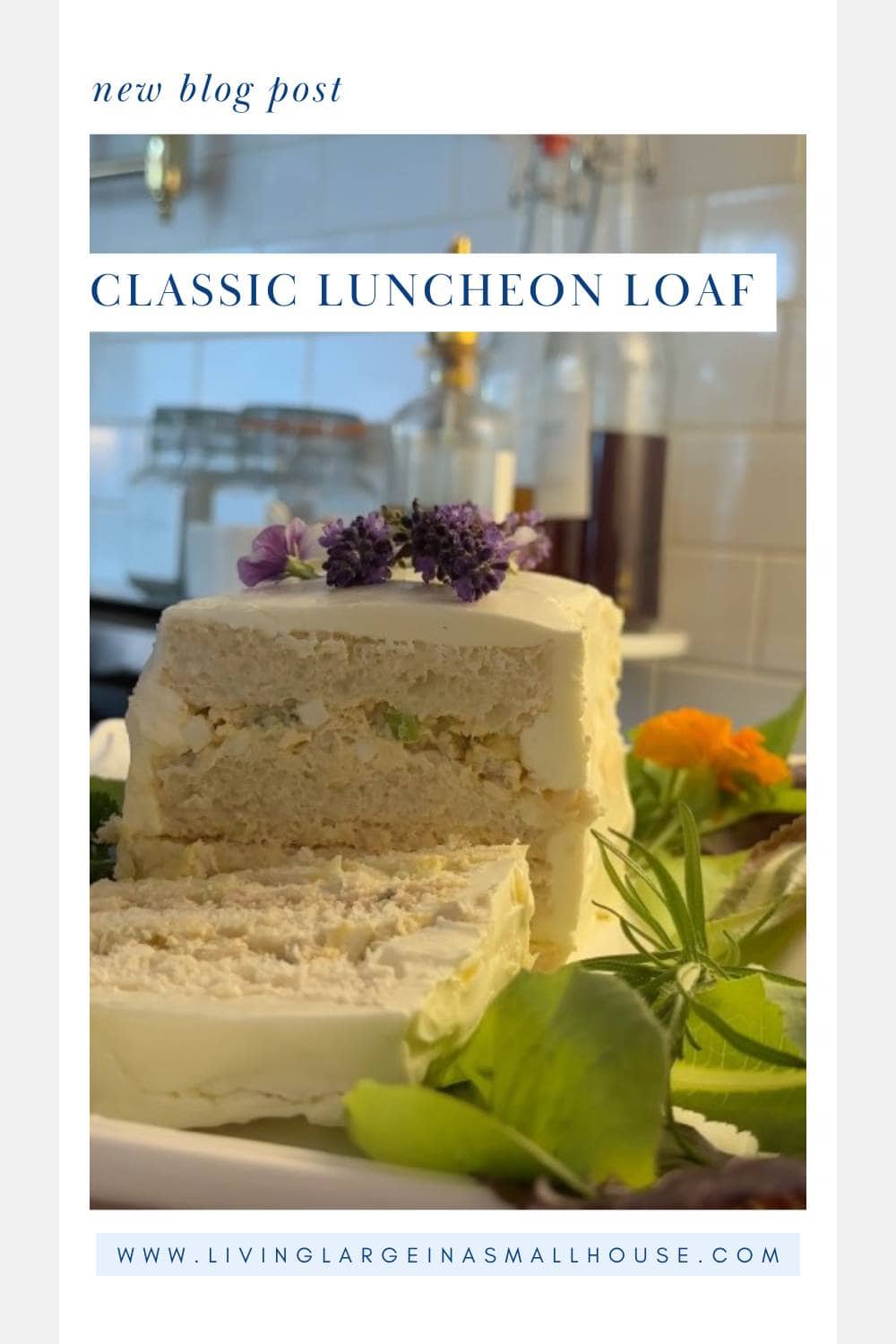 A sliced, frosted luncheon loaf garnished with purple flowers and greens sits on a platter in a kitchen, with glass bottles and a tiled backsplash in the background. Text reads: "Classic Luncheon Loaf" and a blog URL is visible.