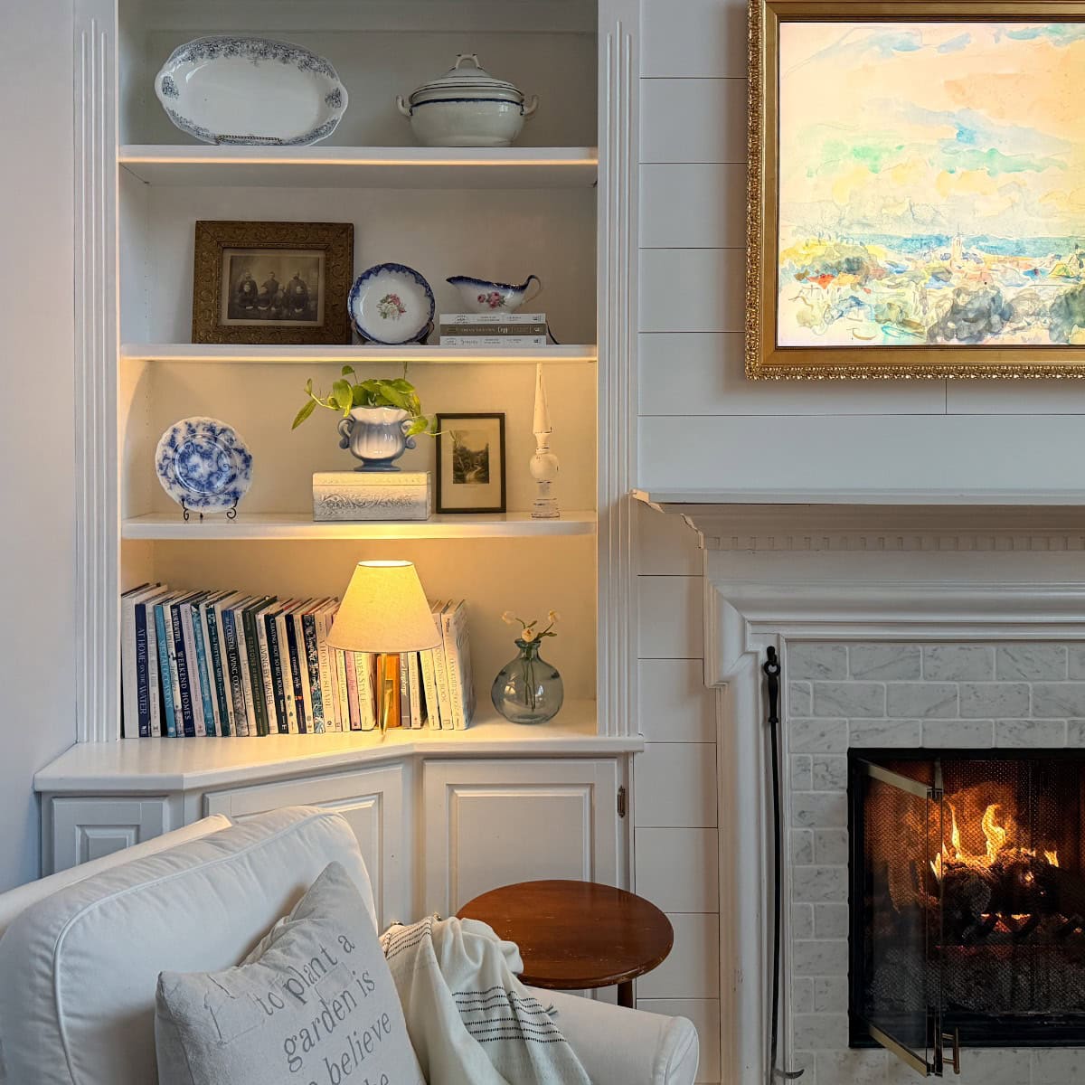 Cozy winter reading nook with an upholstered chair, soft lighting, neutral decor, and built-in shelves styled for a calm winter home.