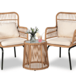 Two wicker armchairs with cream cushions are placed on either side of a round wicker side table with a glass top. Perfect for relaxing after a shopping trip, the table holds a small plant, a pink drink, and a yellow drink against a white background.