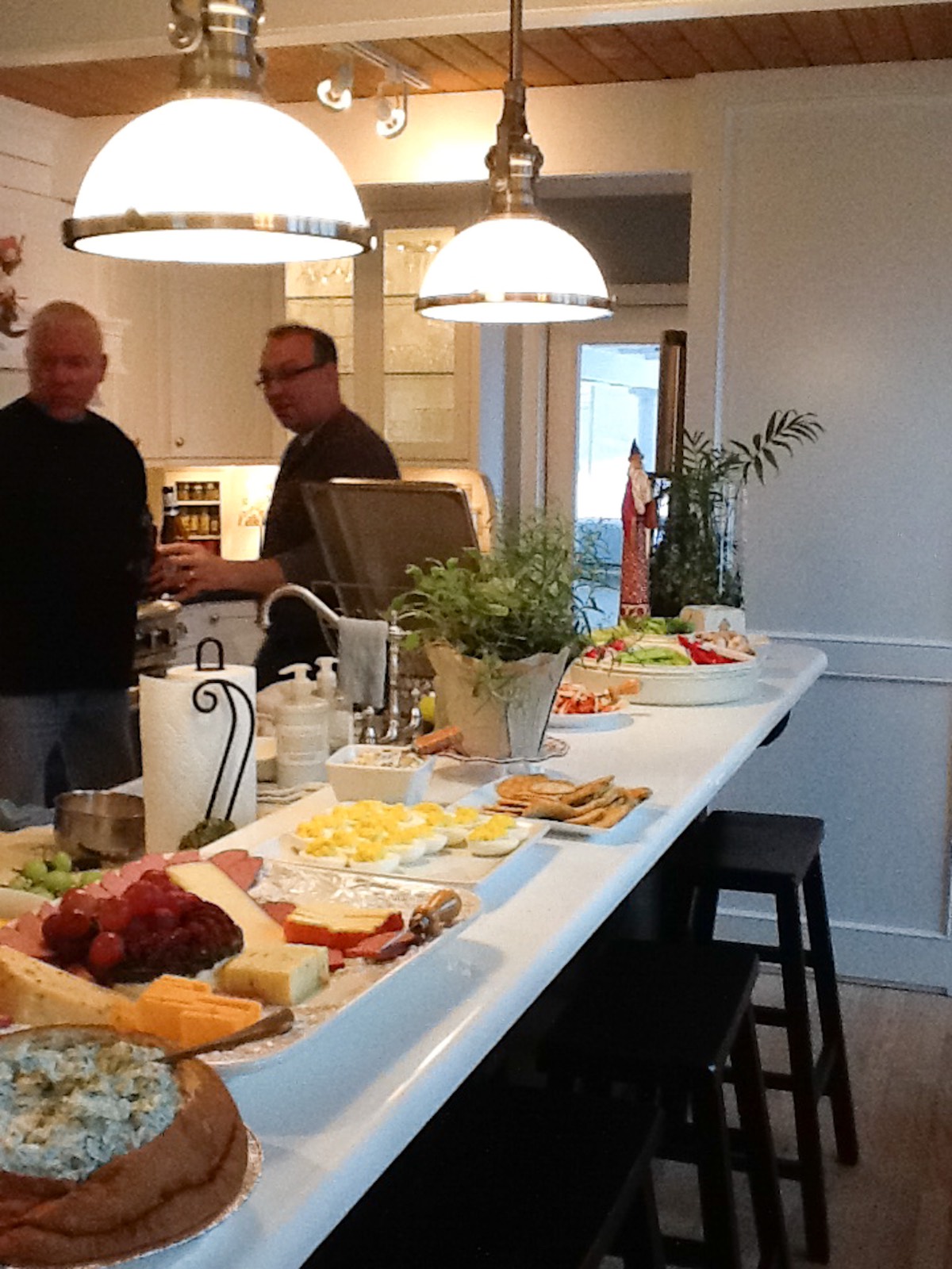 A kitchen island with snacks and cheese, showing how to decorate a small home beautifully under hanging lights.