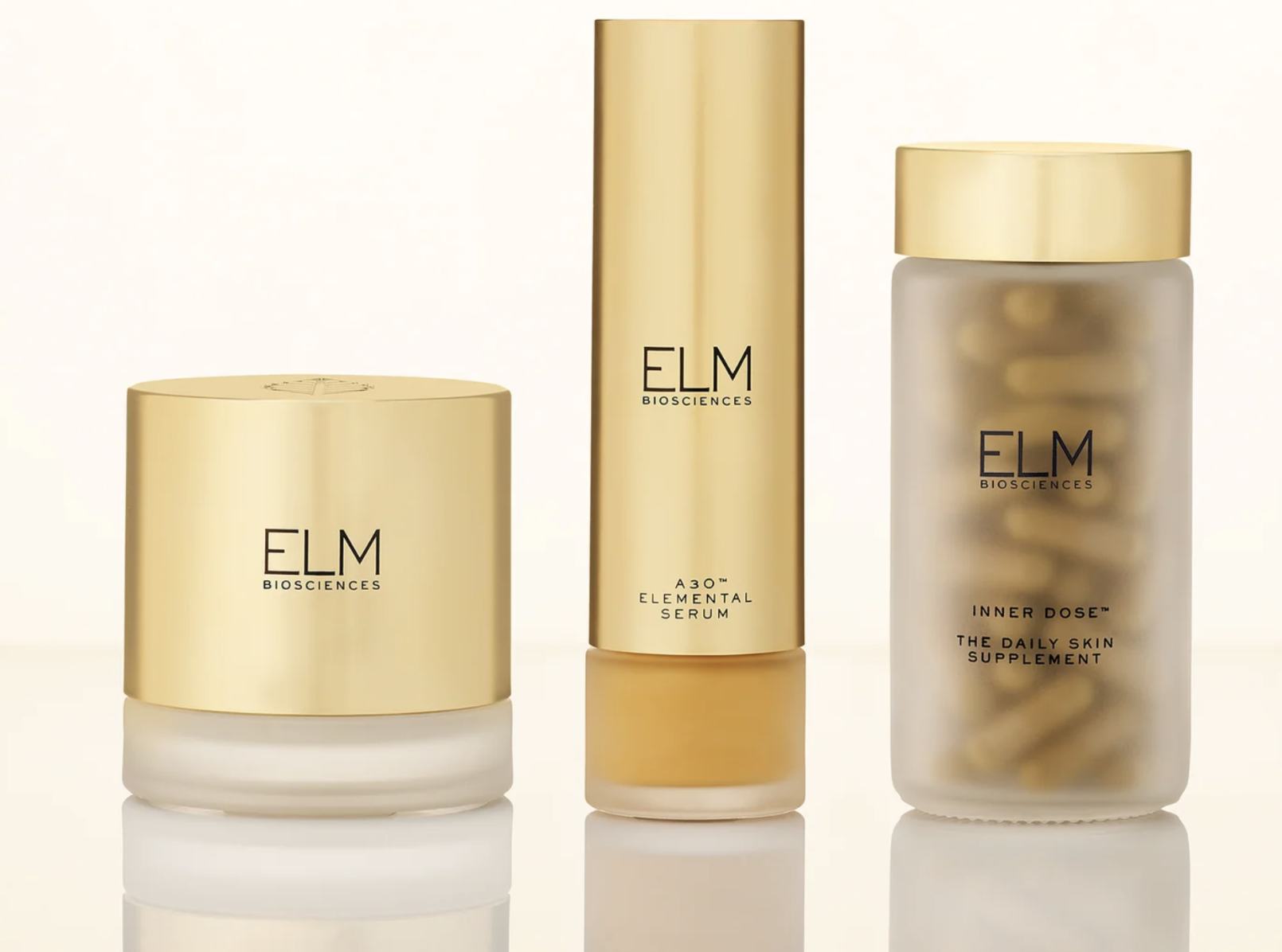 Three gold-capped ELM Biosciences skincare products, perfect for your next shopping haul: cream, serum, and supplements.