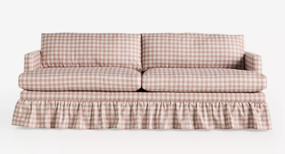 Pink and white gingham sofa with ruffled skirt—perfect to refresh your home for summer, set against a plain white background.