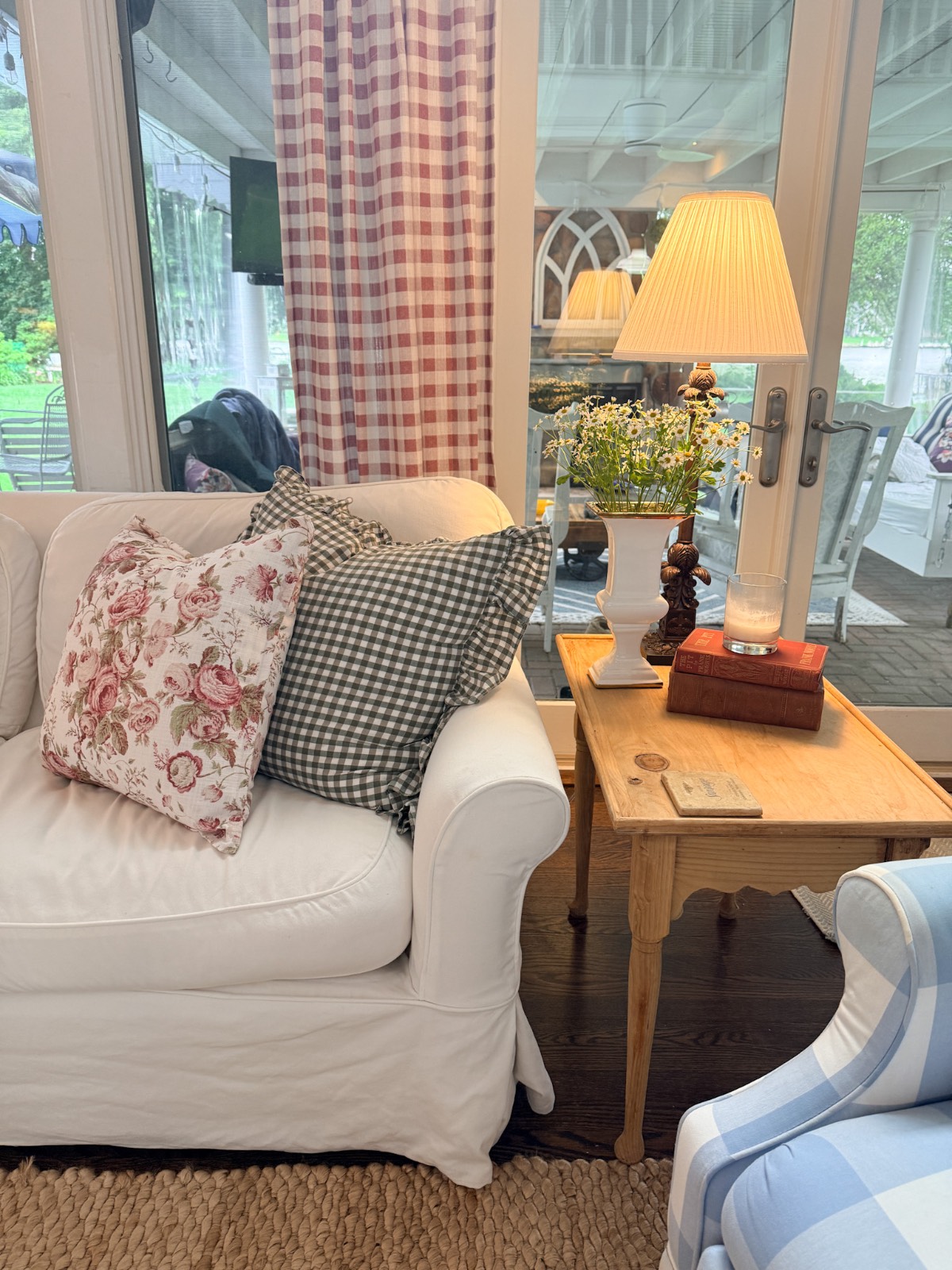 Cozy living room with white sofa and florals—perfect inspo on how to refresh your home for summer by the glass doors.