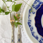 Ornate silver fork and knife show how to decorate a small home beautifully, paired with blue and white china on crisp linen.