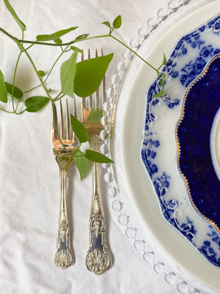 Ornate silver fork and knife show how to decorate a small home beautifully, paired with blue and white china on crisp linen.