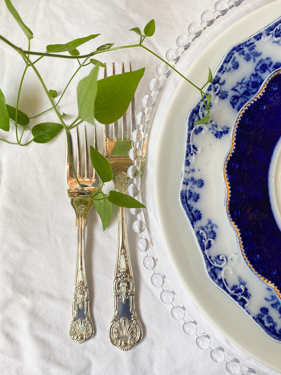 Ornate silver fork and knife show how to decorate a small home beautifully, paired with blue and white china on crisp linen.