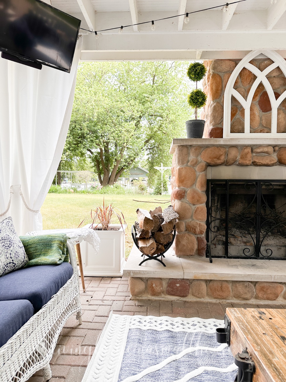 Covered patio with a stone fireplace, outdoor sofa, and tips on how to decorate a small home beautifully.