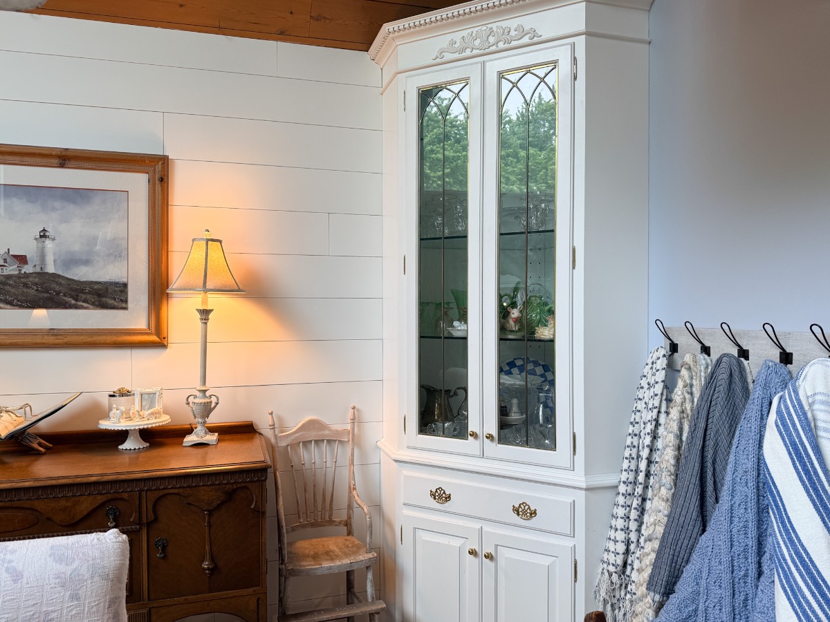 Cozy, cottage-style room shows how to decorate a small home beautifully with a white cabinet, lamp, and wood accents.