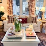 Cozy living room with a white sofa, plaid pillows, and floral curtains—perfect for Christmas in July holiday season planning.